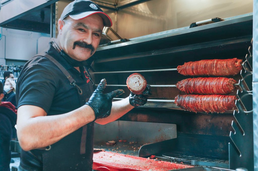 A chef preparing grilled meat in a commercial restaurant kitchen.